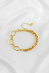 Elegantes Damenarmband aus goldfarbenen Gliedern auf weißem Stoff, Schmuck Accessoire