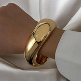 Breiter goldener Armreif aus Edelstahl, handpoliert und 18 K vergoldet, getragen am Handgelenk – LOÉAR Schmuck.