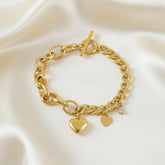 Goldenes Armband mit zwei Herzanhängern und kleinem Kristall auf weißem Hintergrund – LOÉAR Schmuck“