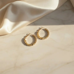 Goldene Creolen Damen mit Zirkonia aus Edelstahl, 18K vergoldet, auf Marmor liegend