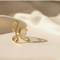 Goldener Damenring mit Zirkonia, skulpturales Design, Edelstahl, auf cremefarbenem Stoff