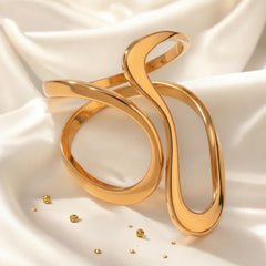 Eleganter goldener Armreif mit wellenförmigem, offenem Design auf glänzendem Seidentuch – moderner Statement-Schmuck von LOÉAR.