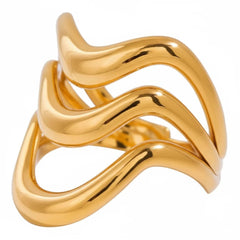 Dreifach übereinanderliegende, wellenförmige goldene Ringe auf einem sanft gefalteten weißen Satinhintergrund. Das Licht betont den warmen Goldglanz und die geschmeidige, organische Form der Ringe.“