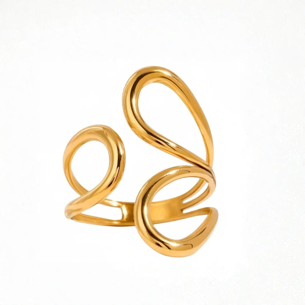 Offener goldfarbener Ring mit organischen, geschwungenen Linien in S-Form, fotografiert auf weißem, weich gefaltetem Satin. Das Licht bringt den warmen Glanz und die glatte Oberfläche des Designs deutlich hervor.