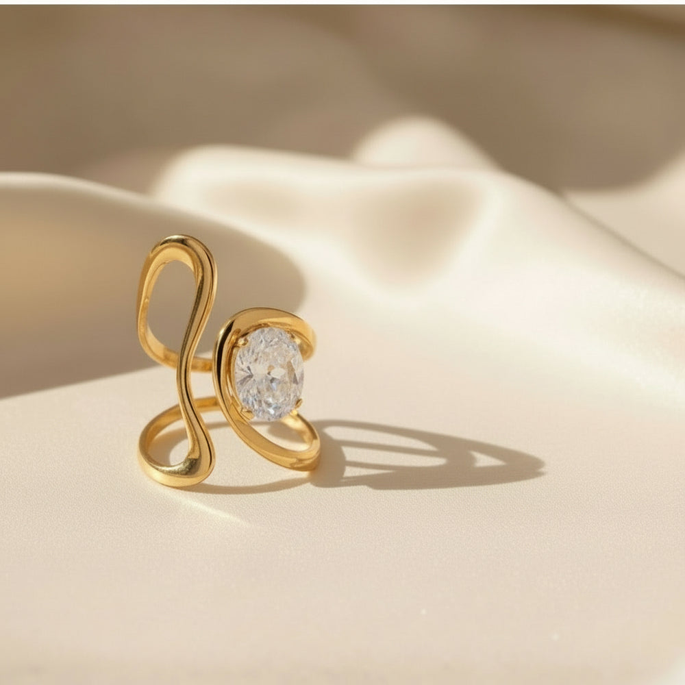 Vergoldeter Designring mit geschwungener, offener Form und funkelndem ovalem Kristall – moderner Statement-Ring aus Edelstahl von LOÉAR.
