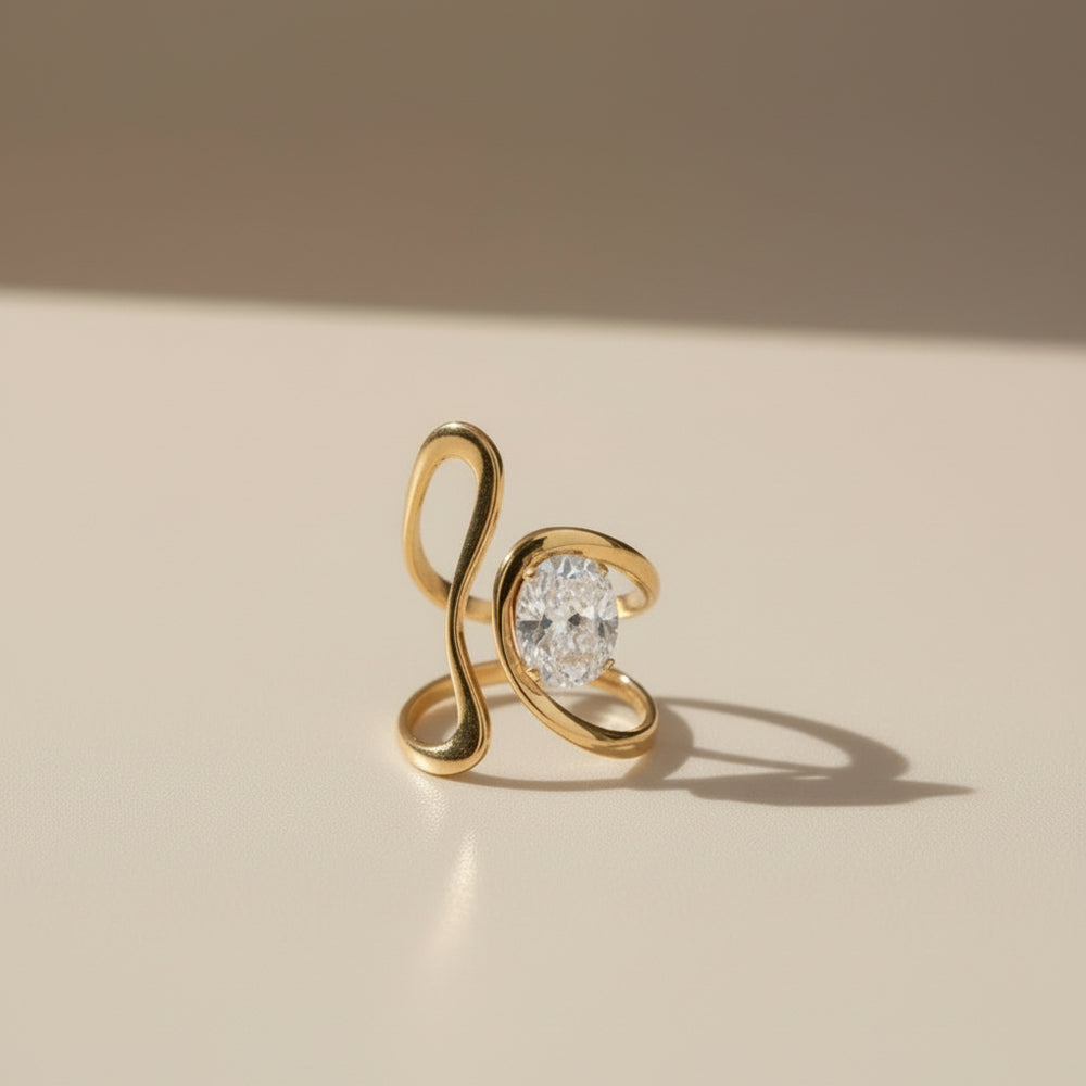 Vergoldeter Designring mit geschwungener, offener Form und funkelndem ovalem Kristall – moderner Statement-Ring aus Edelstahl von LOÉAR.