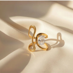 Vergoldeter Designring mit geschwungener, offener Form und funkelndem ovalem Kristall – moderner Statement-Ring aus Edelstahl von LOÉAR.