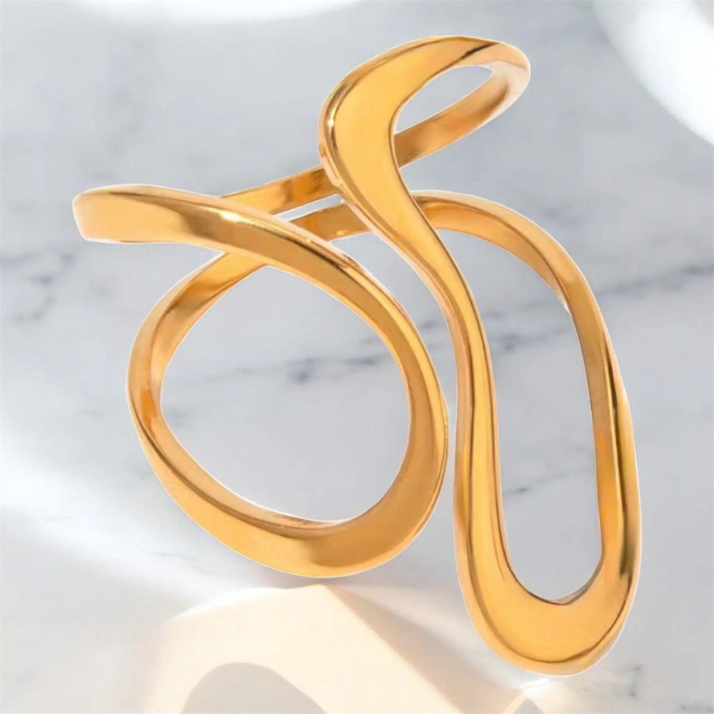 Eleganter goldener Armreif mit wellenförmigem, offenem Design auf glänzendem Seidentuch – moderner Statement-Schmuck von LOÉAR.