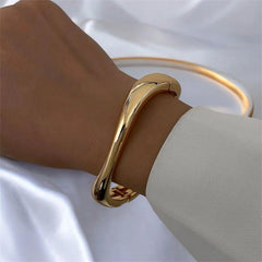 Elegantes Armband in glänzendem Goldton mit fließender, moderner Form – minimalistischer Armreif von LOÉAR, getragen am Handgelenk.